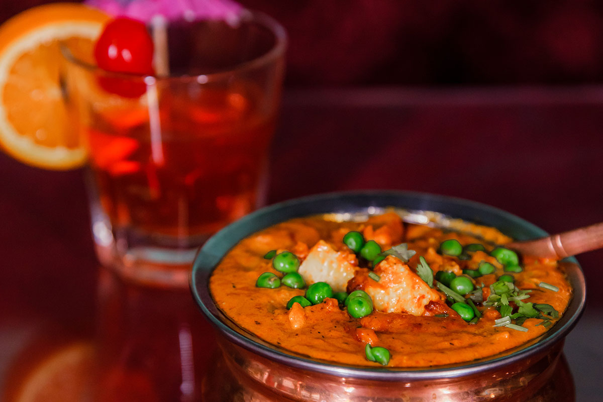 A delicious bowl of classic Chicken Tikka Masala from Mint Indian Restaurant, featuring a rich, creamy tomato sauce and a garnish of fresh cilantro.