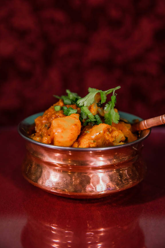 A delicious bowl of classic Chicken Tikka Masala from Mint Indian Restaurant, featuring a rich, creamy tomato sauce and a garnish of fresh cilantro.