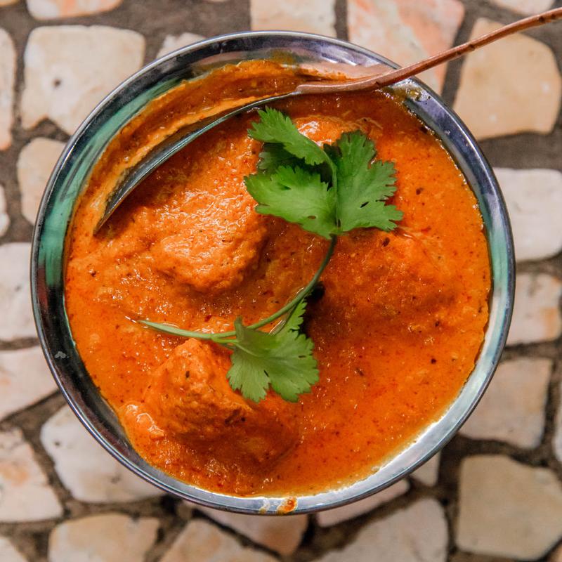 A delicious bowl of classic Chicken Tikka Masala from Mint Indian Restaurant, featuring a rich, creamy tomato sauce and a garnish of fresh cilantro.