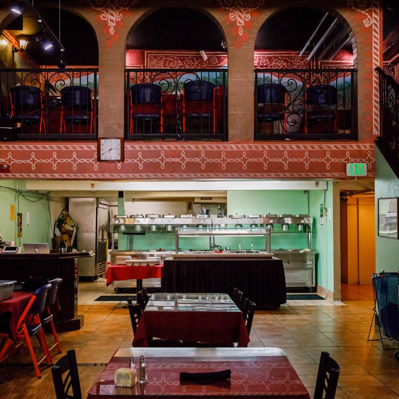 The spacious, two-level interior of Mint Indian Restaurant in Denver, featuring a main dining floor, a buffet line, and a unique upper mezzanine with decorative arches.