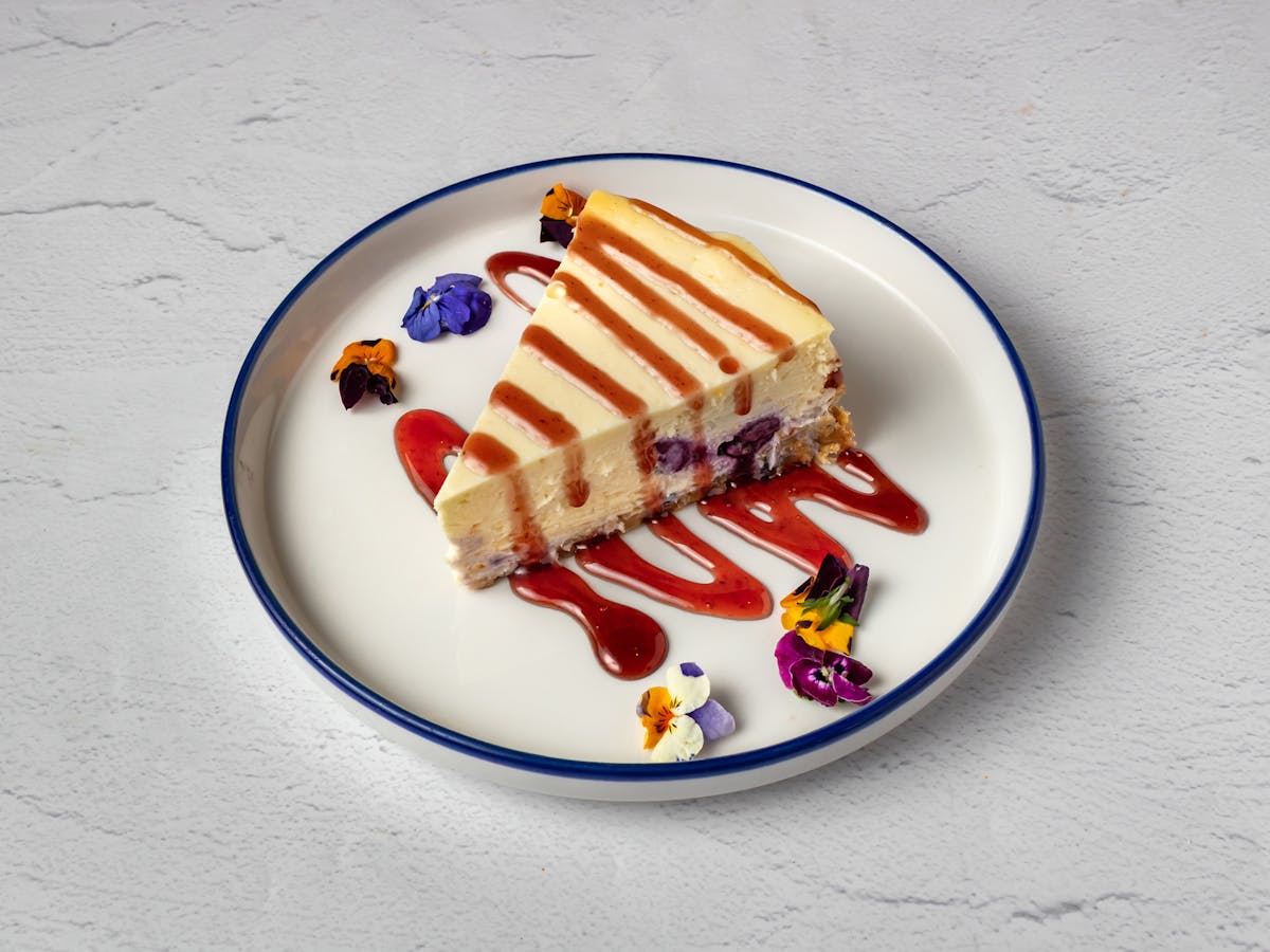 Blueberry Cheesecake with fresh berry sauce drizzle — house-made dessert at Amici Brick Oven Pizza, West Palm Beach