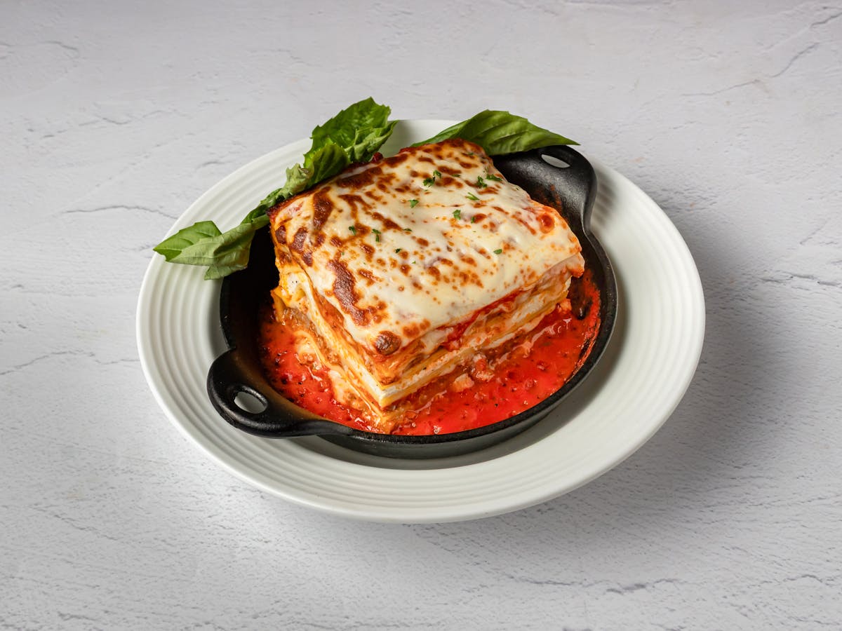 Homemade lasagna with marinara, melted mozzarella, and fresh basil — Italian comfort food at Amici Brick Oven Pizza, West Palm Beach