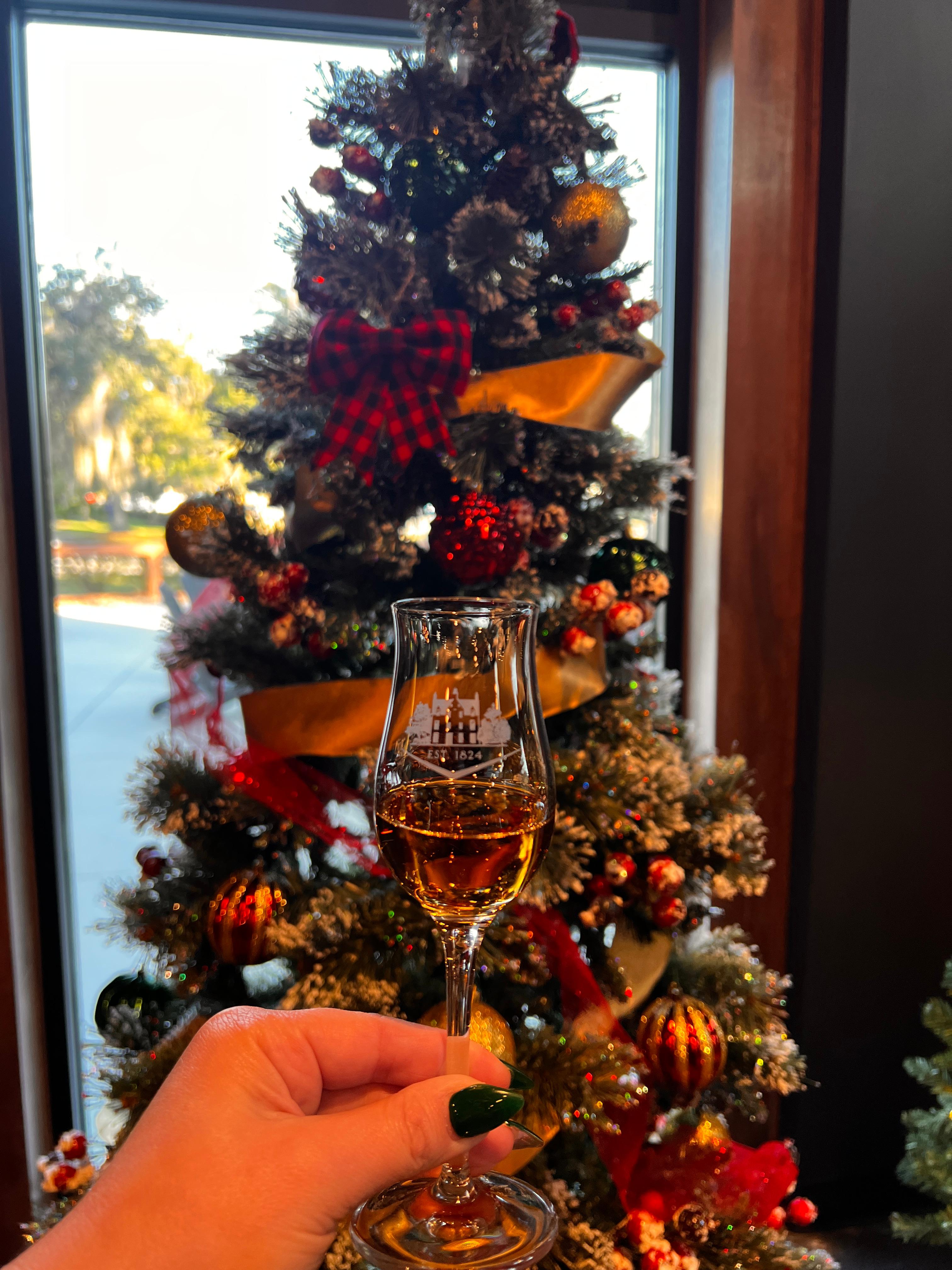 A glass of Macallan in a Macallan glass in front of a decorated christmas tree