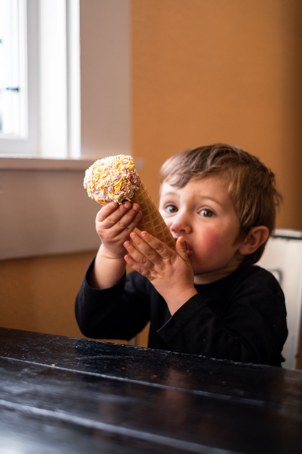 Little boy eating locally made Cowlick's ice cream in a waffle cone at Frankie's Pizza & Ice Cream in Mendocino, California